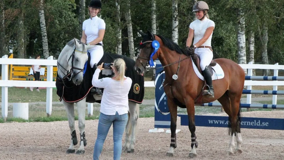 Linnea Ericsson-Carey och Julia Johansson gratuleras till meetingpris av tävlingsledaren Sofia Bengtsberg som även förevigar de två.