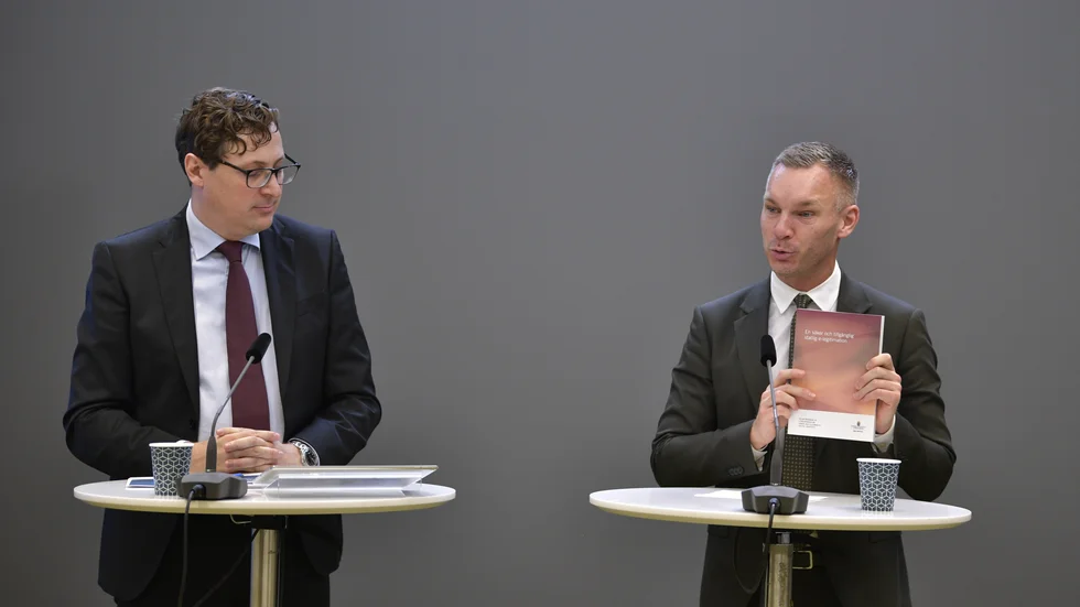 Civilminister Erik Slottner (KD) med delbetänkandet från utredningen om säker och tillgänglig digital identitet. Till vänster utredare Henrik Ardhede.