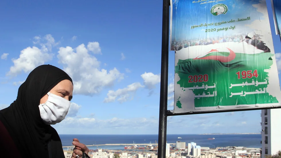 En kvinna i Algeriets huvudstad Alger går förbi en skylt som uppmanar folk att rösta för den nya grundlagen.