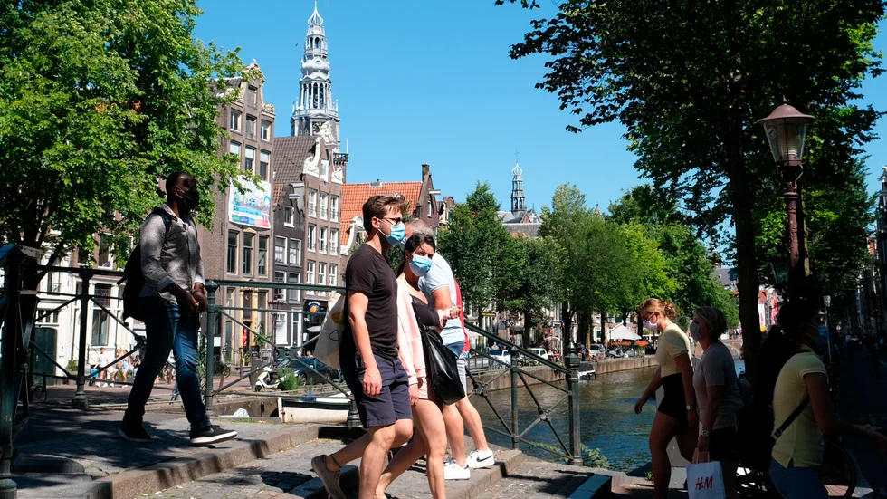 Människor promenerar över en bro i Nederländernas huvudstad Amsterdam, där krav på munskydd nyligen införts på vissa platser.