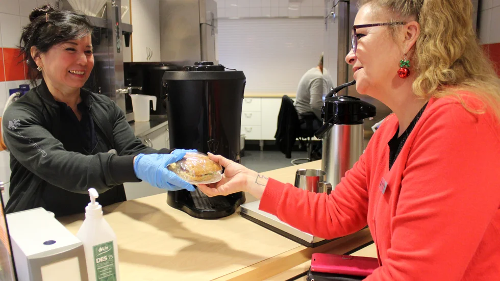 Rano Madaminova serverar en smörgås till skolvärdinnan Anette Lindberg, som var mentor för Rano, när hon började arbeta i kaféet.