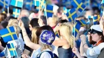 Publiken viftar med svenska flaggor under nationaldagsfirandet med kungafamiljen på Sollidenscenen på Skansen i Stockholm.