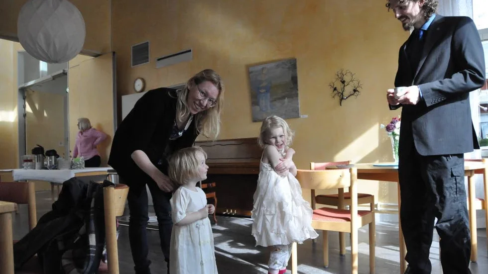 Dopfin. Ylva Brattfält fixar till klänningen för Lea som ska döpas. Storasyster Alice och pappa Marc tittar på.