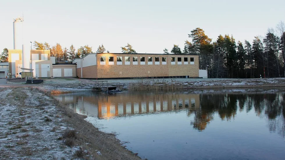 En av  infiltrationsdammarna med vattenverket i fonden, vattnet forsar in i bortre änden av dammen, invid bryggan.