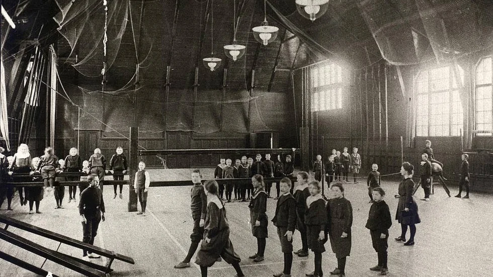 Folkskola. Även flickorna skulle gå i skolan i och med att förordningen om allmän folkskola kom år 1842. Bilden är från 1907. En gymnastiklektion i en skola i Stockholmsförorten Djursholm. Lärare är fröken von Bahr som står till höger och i handen har boken med Dagövningar.