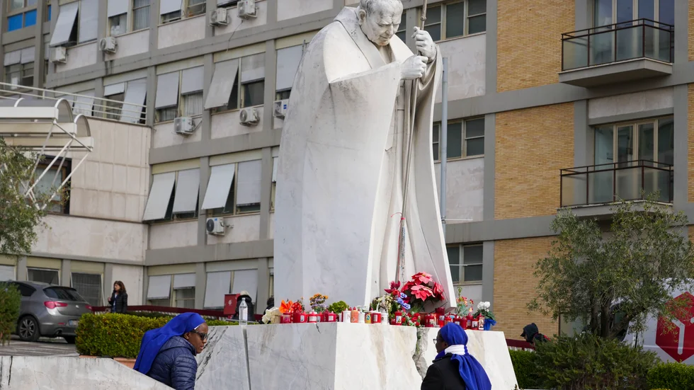 Nunnor lägger blommor vid en staty av påve Johannes Paulus II framför Gemelli-kliniken i Rom.
