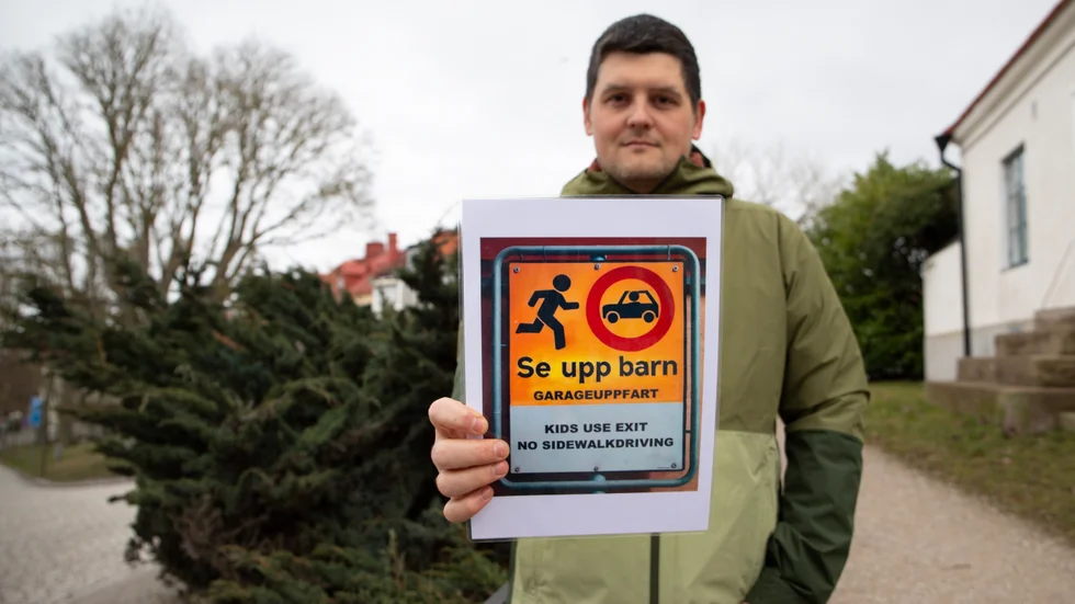 Artur Hansson visar upp en egengjord skylt. Tidigare satte han upp en reflexskylt för att få bilisternas uppmärksamhet i mörkret – men den plockades bort. 