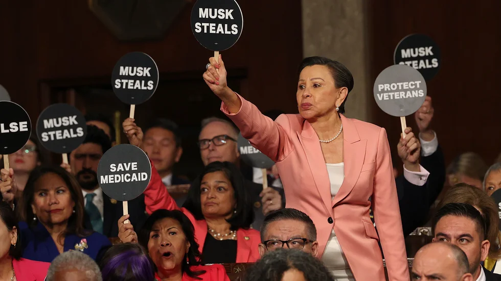 Demokratiska kongressledamoten Nydia Velázquez håller upp en skylt där det står "Musk stjäl" under Donald Trumps tal till kongressen.