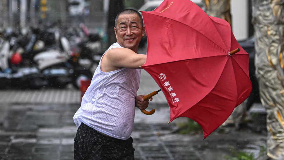En optimistisk man i Haikou på Hainan gör ett försök att använda paraply trots tyfonen på fredagen.