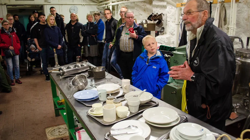 Guiden Ralf Adolfsson visar runt besökarna inne i fortet. Bilden är tagen vid en visning för några år sedan. Här inne syns köket och Kronans porslin.