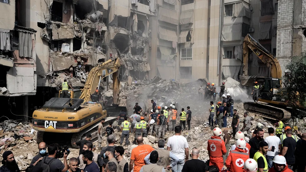 Räddningsarbetare använder grävmaskiner för att rensa bland bråten efter fredagens flyganfall i södra Beirut.