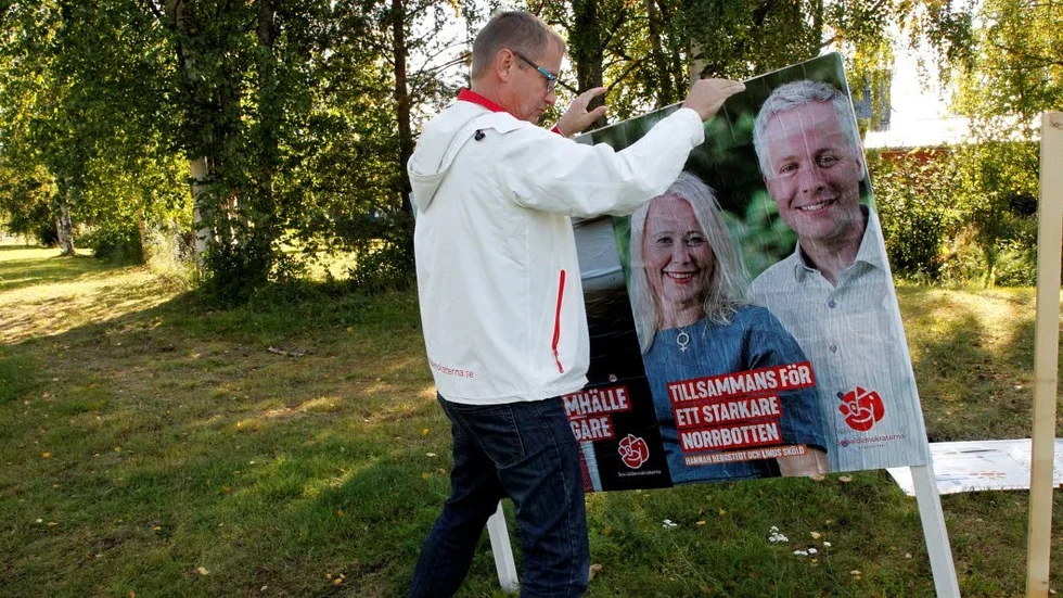 Tomas Egmark lyckas trycka fast plakatet lite snett i väntan på att de får dit några verktyg och kan sätta upp det ordentligt igen.
