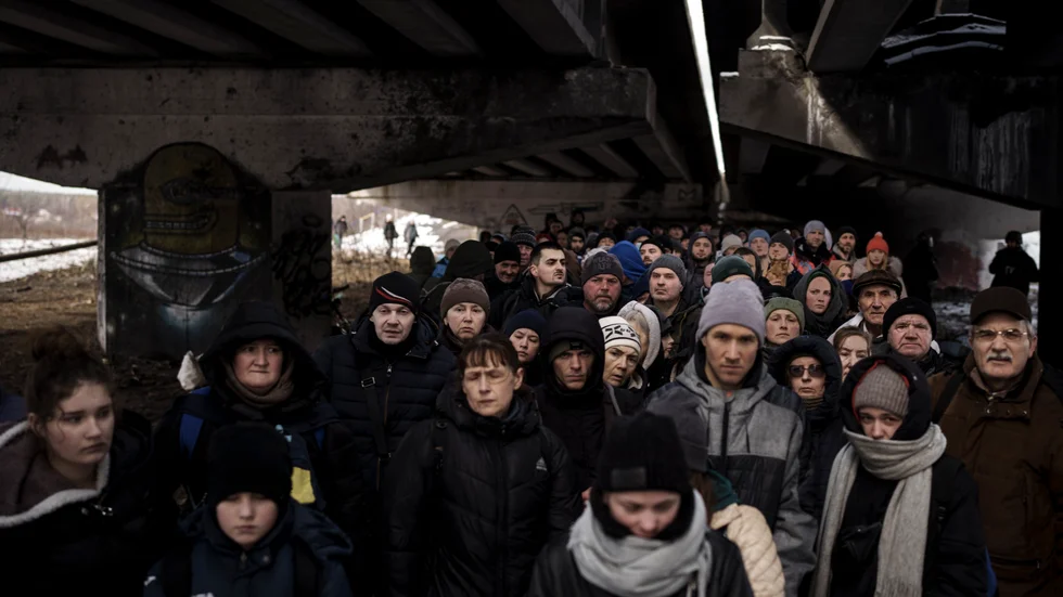 Ukrainska flyktingar samlade under en förstörd bro i närheten av Kiev.