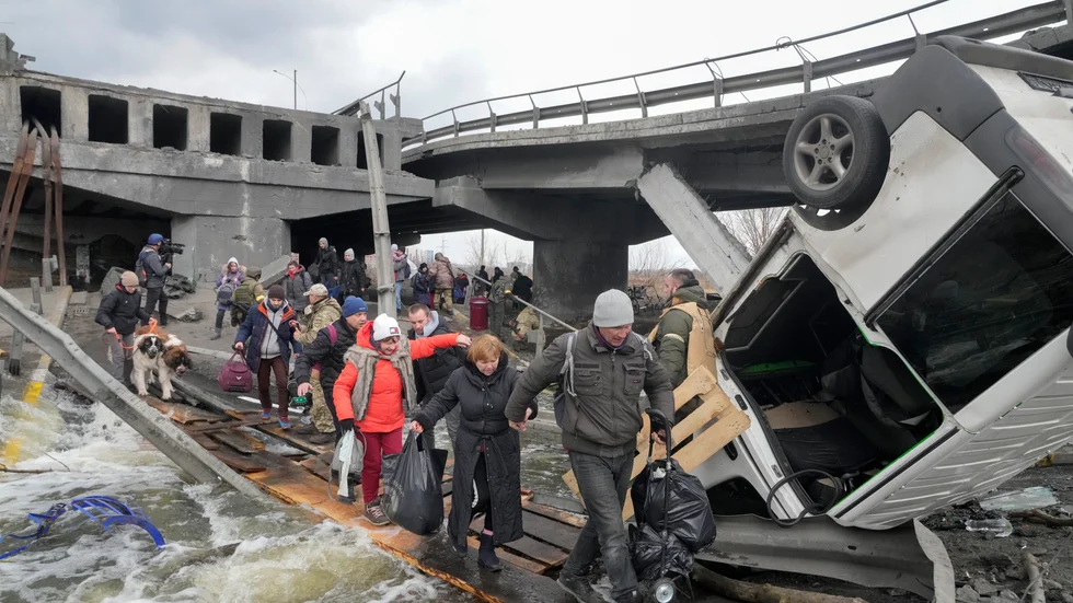 Människor på flykt från samhället Irpin i utkanten av Kiev via en provisorisk övergång vid den förstörda bron på måndagen.