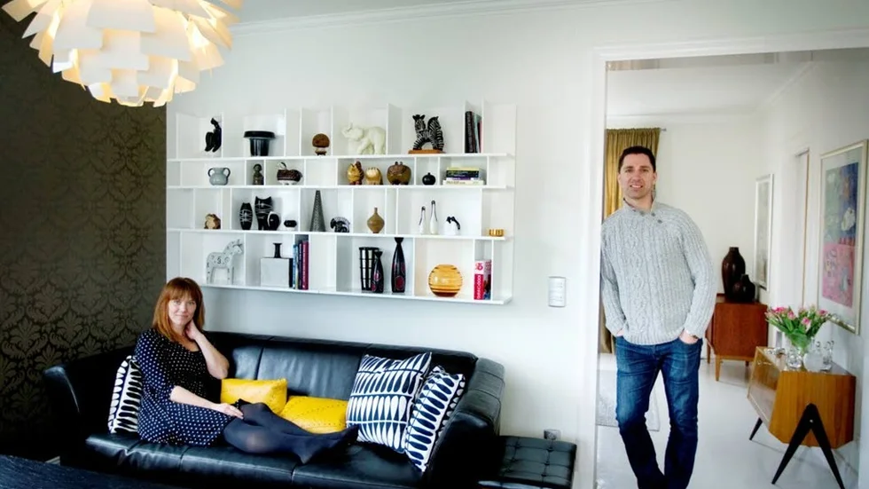 Prylplats. Jessica och Janne Hillerström, här tillsammans i vardagsrummet med några av sina finaste ägodelar. Prylhyllan från Boconcept som de köpte på Blocket och som nu är hem åt många av de 		fynd de gjort under åren. Här flyttas det ständigt runt bland pryttlarna och Jessica använder ofta hyllan som uppställningsplats när hon fotar sina nya fynd som hon sedan publicerar på sin blogg eller på Instagram. Lampan ”Kotten” som formgavs av Poul Henningsen för Lous Poulsen 		1958 är en kär familjemedlem inköpt på Uppsala Auktionskammare.