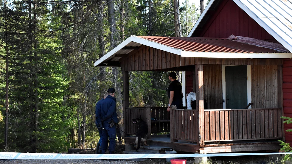 Hundförare och polisens tekniker går igenom flottningsstugan dagen efter att offret påträffats i den brinnande bilen.