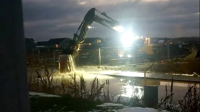 Här öser grävmaskinen ut skopa efter skopa med vatten från byggarbetsplatsen över gatan.