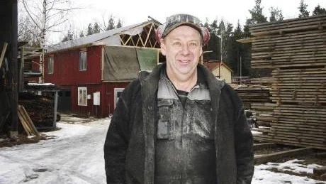 Gårdsplanen vid Gladhammars Såg är  fullpackad med såväl hyvlade bräder som stora timmerstockar. Hasse Bertelsen trivs att ha mycket jobb i den hårda konkurrensen i träbranschen.