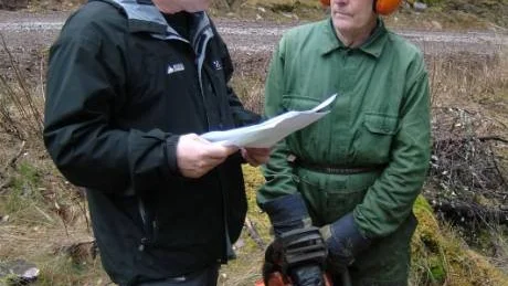 Karl-Gunnar Karlberg, som arbetar för skogsföretaget Bergs, visar Gösta Andersson, till höger, papper på hur mycket som blev över efter avverkningsuppdraget.Foto: Lena Pettersson