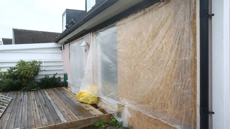 Byggplast. Stora hål i väggarna där fönstren skulle ha suttit. Plasten blåser rakt in i huset.