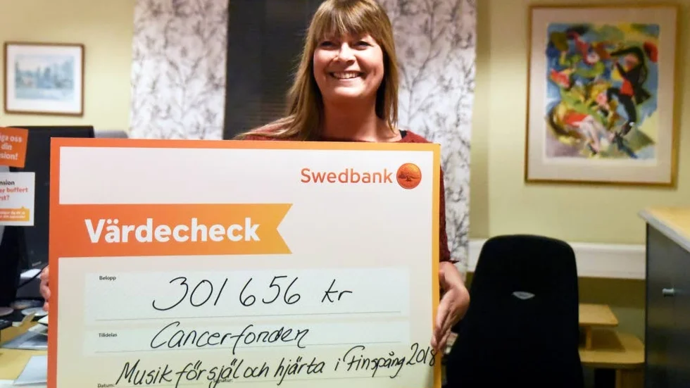 Pernilla Härnbro, kontorschef Swedbank i Finspång, med checken som Per-Erik Störe ska lämna på Cancergalan i Stockholm 7 januari.