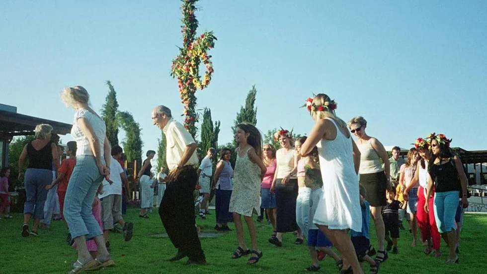 Här skuttar svenskar som bor på Cypern runt en midsommarstång. I den engelska bildtexten står att svenskarna dansar runt "a fertility symbol".