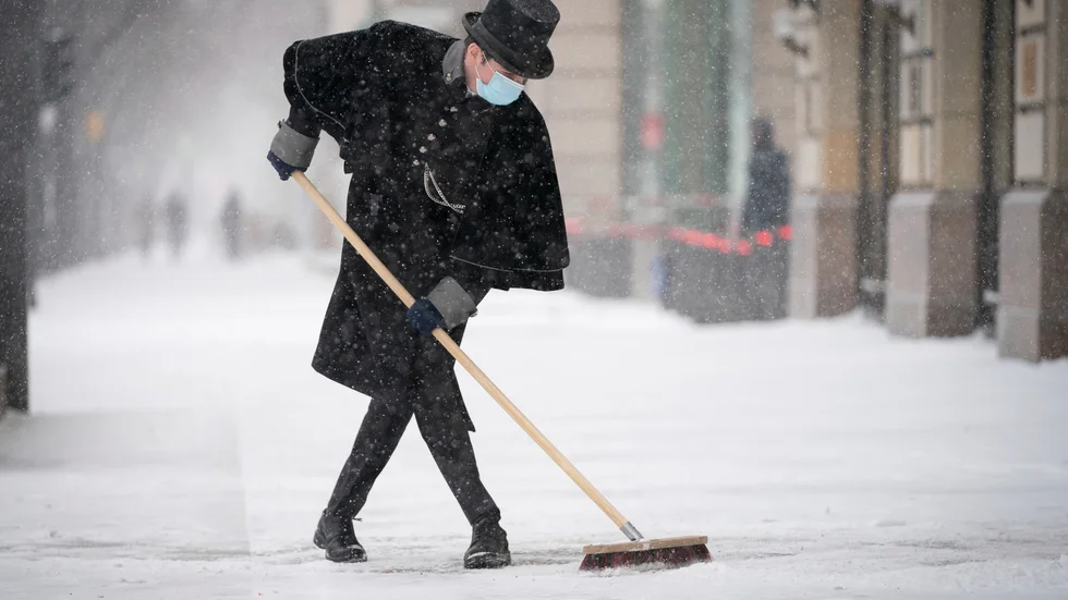 En anställd försöker hålla snön stången framför lyxhotellet Adlon i Berlin. Bild från i måndags.