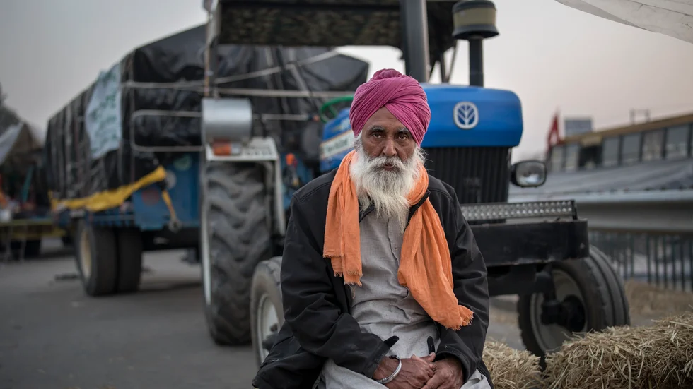 Jordbrukaren Atma Singh, 62 år, poserar framför sin traktor som står parkerad på motorvägen vid gränsen mellan delstaterna Delhi och Haryana. Jordbrukarna befarar att jordbruksreformer kommer göra att de hamnar i klorna på storföretag. Arkivbild.