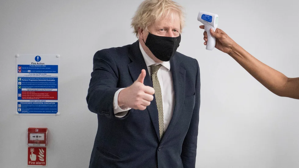Storbritanniens premiärminister Boris Johnson tar tempen under ett besök på måndagen på ett sjukhus i norra London. Inom kort väntas han ge besked om strängare nedstängningsregler från och med midnatt, natten till tisdag.