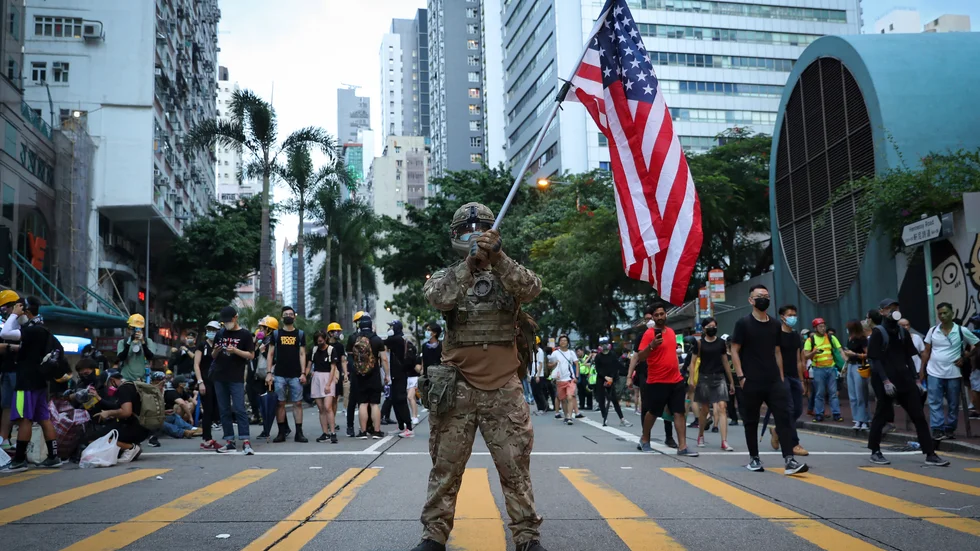 En demonstrant utklädd till militär håller en amerikansk flagga under demokratiprotester i Hongkong i augusti 2019.
