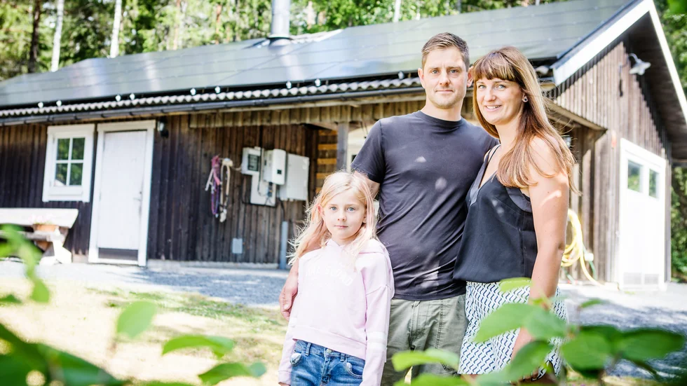 Johan och Emilia Lönn med dottern Tyra vid garaget där solcellsanläggningen sitter. Sonen Teodor var inte hemma vid fotograferingstillfället.