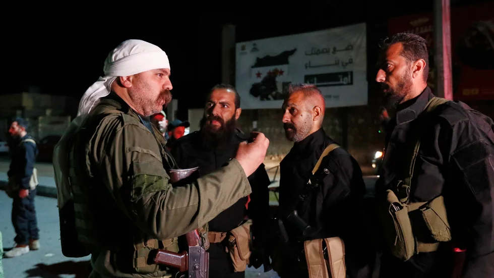 En man från drusers väpnade styrkor (till vänster) talar med män från syriska regeringsstyrkor, sedan druserna och regeringen enats om att soldater ska placeras ut kring ett drustätt område utanför Damaskus. Bilden togs i fredags morse.