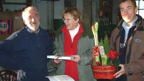 Här uppvaktas Göran Nilsson på bilverkstaden av Monika Lindh och Jan-Inge Gustavsson med blommor och presenter.