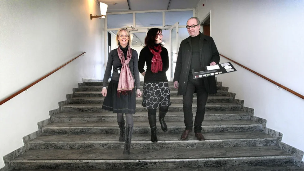 Marietta Douglas, Eva Nyström Tagesson i stora trapphallen med ombyggnadsarkitekten Göran Göransson och en färgprovskarta. Diskussionerna och undersökningarna blir många. Hur ska den sandbruna färgen exakt se ut? Bild: MIKAEL SVENSSON