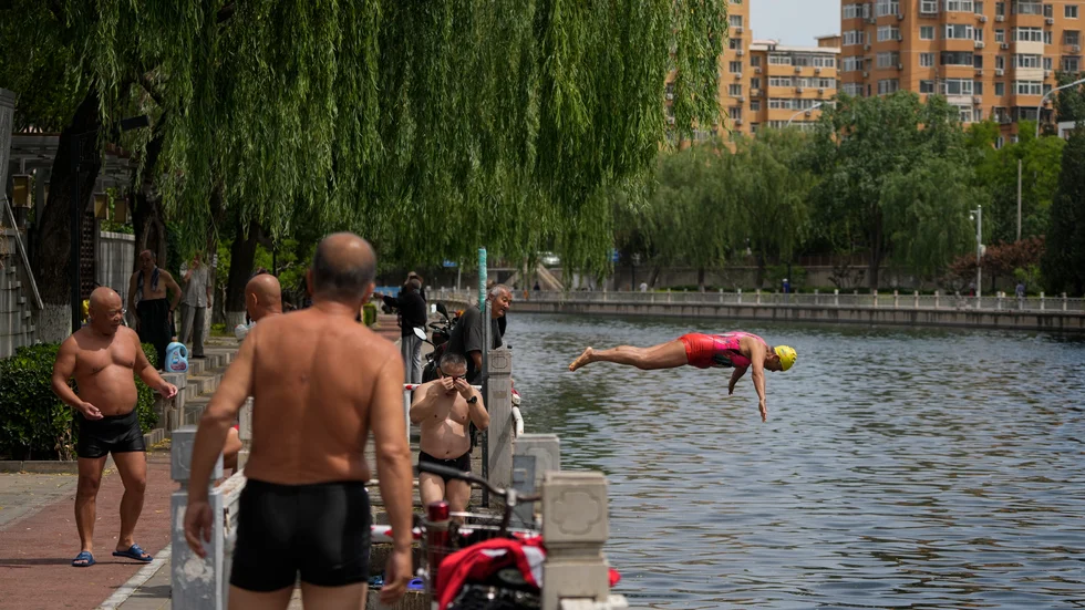 Nya värmerekord har slagits de senaste veckorna på flera håll i Sydost- och Sydasien. På bilden en kvinna som dyker i en kanal i Peking.