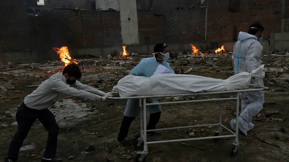 En person som avlidit med covid-19 rullas in till ett område som gjorts om till krematorium i Indiens huvudstad New Dehli. Landet är just nu hårt drabbat av en ny covidvåg.