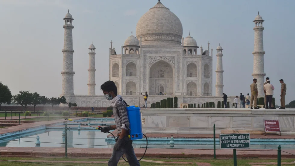 En man desinficerar området runt mausoleet Taj Mahal i Agra, Indien. Det världsarvslistade monumentet öppnade på onsdagen efter att ha varit stängt sedan april på grund av pandemin.