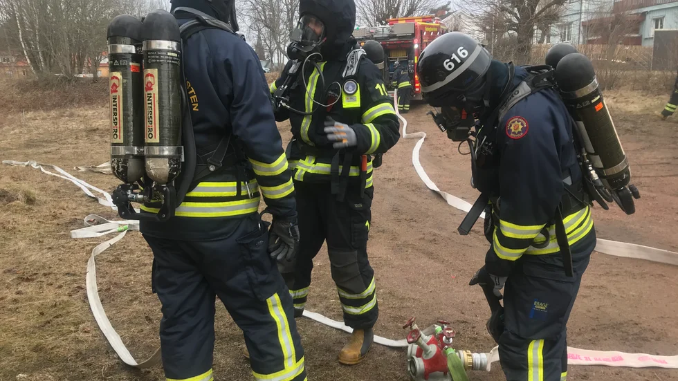 Brandmännen tar på utrustning för rökdykning och slangar rullas ut.