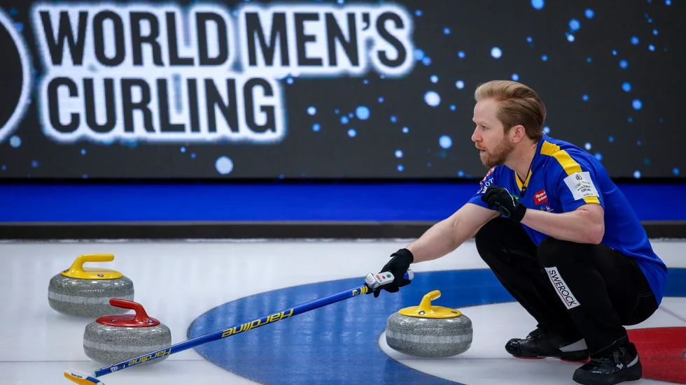 Sveriges skipper Niklas Edin visar hur lagkamraterna ska slå en sten under curling-VM.