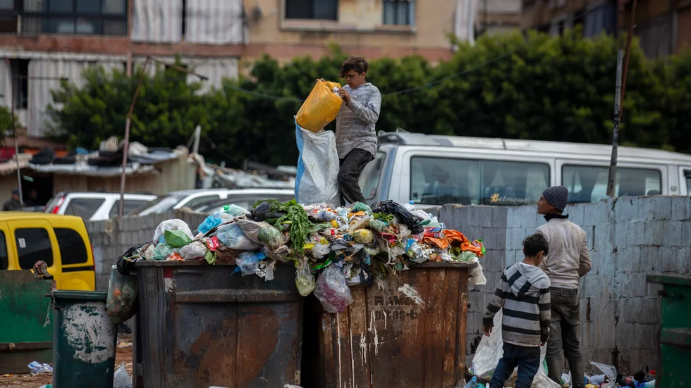 Barn letar efter något av värde i soporna bredvid en marknad i Beirut.