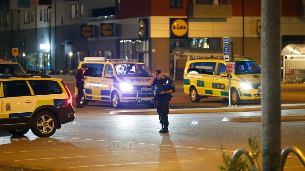 Poliser och ambulans i Flemingsbergs centrum, efter att en person hittats med misstänkta skottskador utomhus.