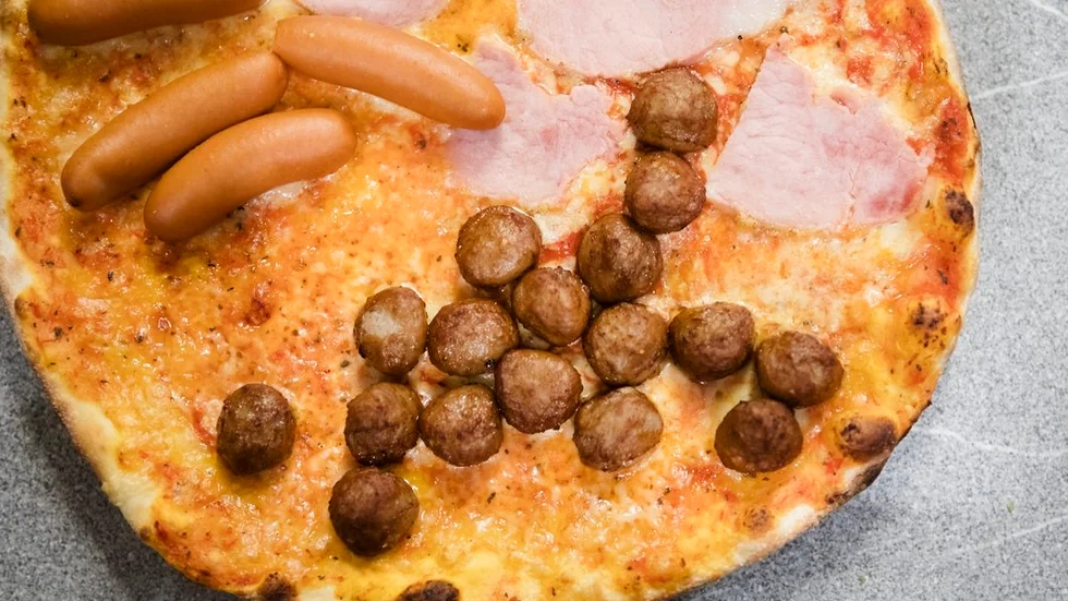Prinskorv, julskinka, senap och köttbullar pryder pizzan.