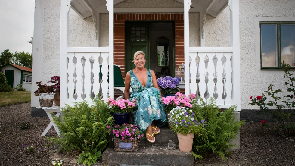 Marie Holmén på trappen till sin husdröm. I den krattade grusgången aktas de självsådda penséerna som tittar upp som små busiga buskar här och där.