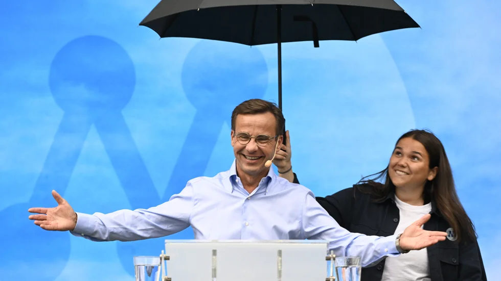 Ulf Kristersson talade på måndagsförmiddagen i Almedalen. Medarbetare fick bistå med regnskydd.