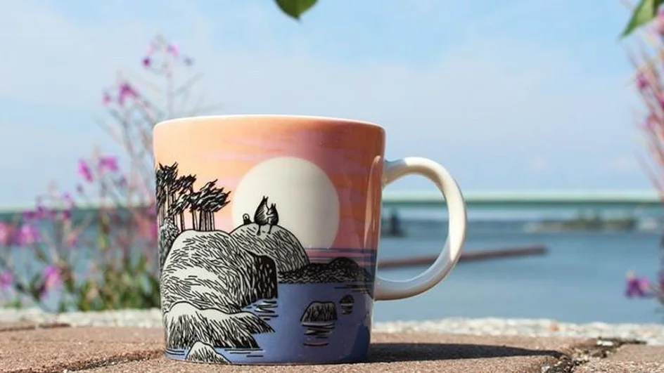 Motivet på muggen med namnet "Mumindagen" har illustrerats av Tove Jansson. På teckningen har Mumintrollet och Muminmamman klättrat upp på ett högt berg på en närbelägen ö för att beundra solnedgången. Bilden vittnar om Tove Janssons betydelsefulla förhållande till sin egen mamma.