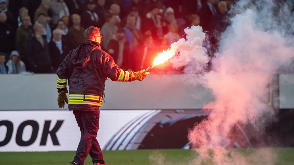 Personal tar hand om en inkastad bengal under skandalmatchen mellan Malmö FF och Union Berlin. Arkivbild.