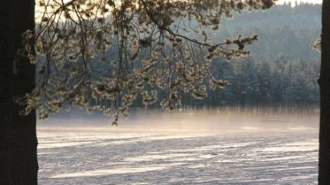 Solen strålar över Nyborgstjärn i Arvidsjaur och i växlingarna mellan varmt och kallt bildas små dimstråk.