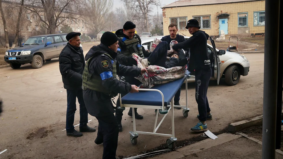Ukrainska militärer och frivilliga bär en skadad man under en attack mot ett sjukhus i Mariupol under tisdagen.
