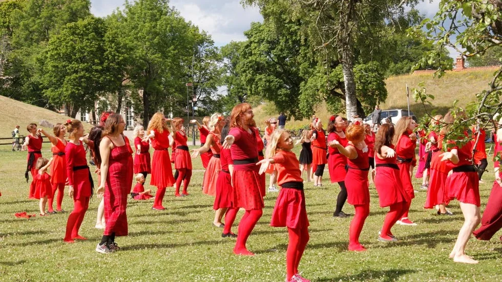 Små och stora, mest kvinnor men också en del män kom till Gamla Uppsala för att tillsammans och i röda kläder dansa som på Kate Bush's musikvideo.