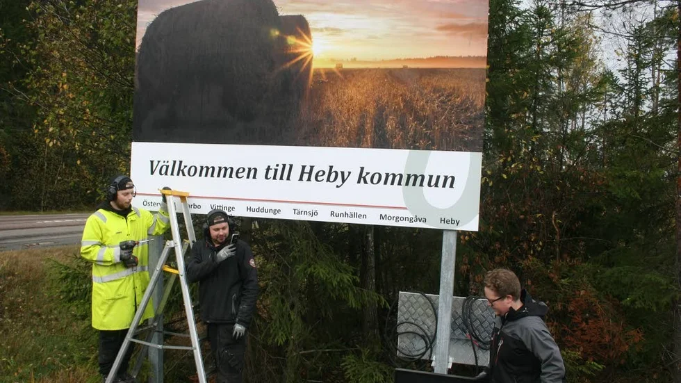 Skylten på plats. Välkomstskylten längs riksväg 72 vid infarten till Vittinge, där Hebyfotografen Johan Winbäck Lennartsson bidragit med bilden, kommer på plats genom Mats Danielsen, Sebastian Tägtström och Eric Gunnarsson från det Leksandsbaserade skyltföretaget Nordsign AB.